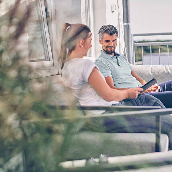 Zwei Mitarbeitende einer Agentur in Hannover sitzen auf einer Bank der Terrasse ihres Büros.