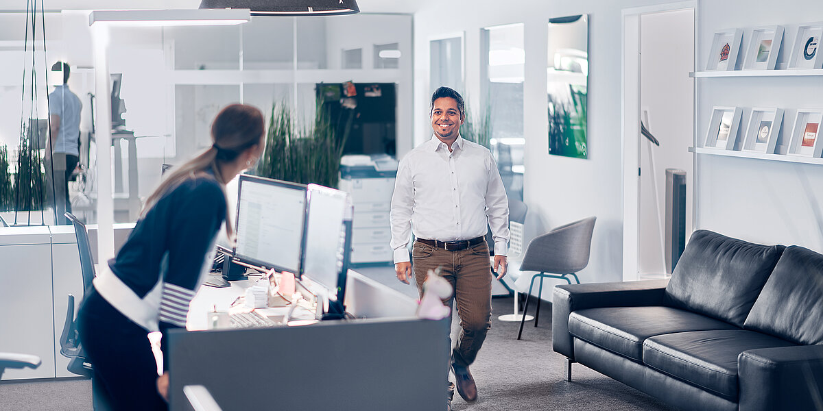 Frontdesk einer Agentur für digitales Marketing in Hannover. Eine Mitarbeiterin begrüßt einen vorbeigehenden Kollegen.