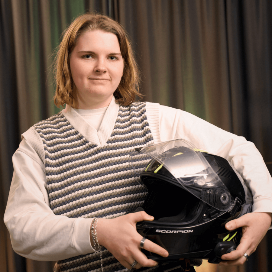 Samantha, Webentwicklerin bei der B2B Digitalagentur digit.ly in Hannover, posiert mit einem Motorradhelm unterm Arm.