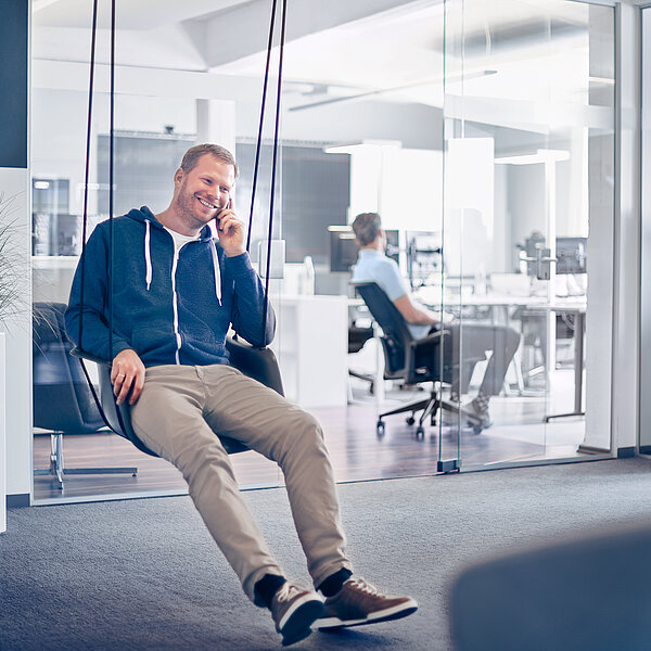 Mitarbeiter einer B2B Digitalagentur sitzt auf einer Schaukel in der Lounge der Agentur.