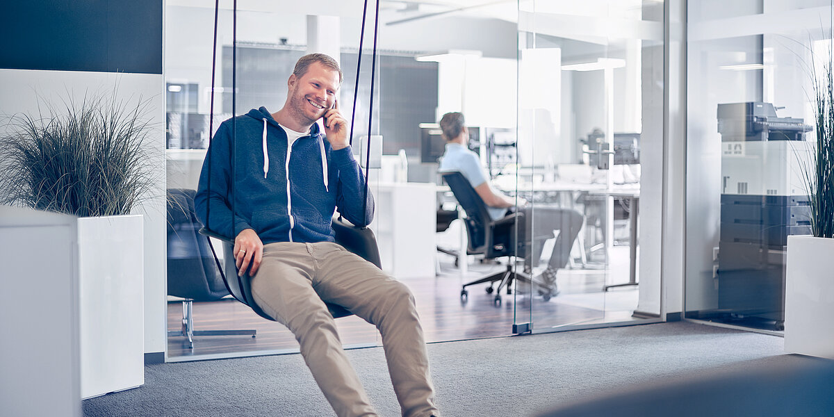 Mitarbeiter einer B2B Digitalagentur sitzt auf einer Schaukel in der Lounge der Agentur.