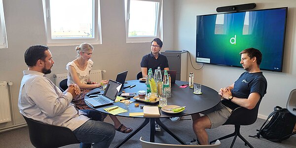 Vier Mitarbeitende einer Agentur für Webentwicklung in Hannover sitzen um einen Tisch und nehmen an einem Workshop zur Customer Experience teil.