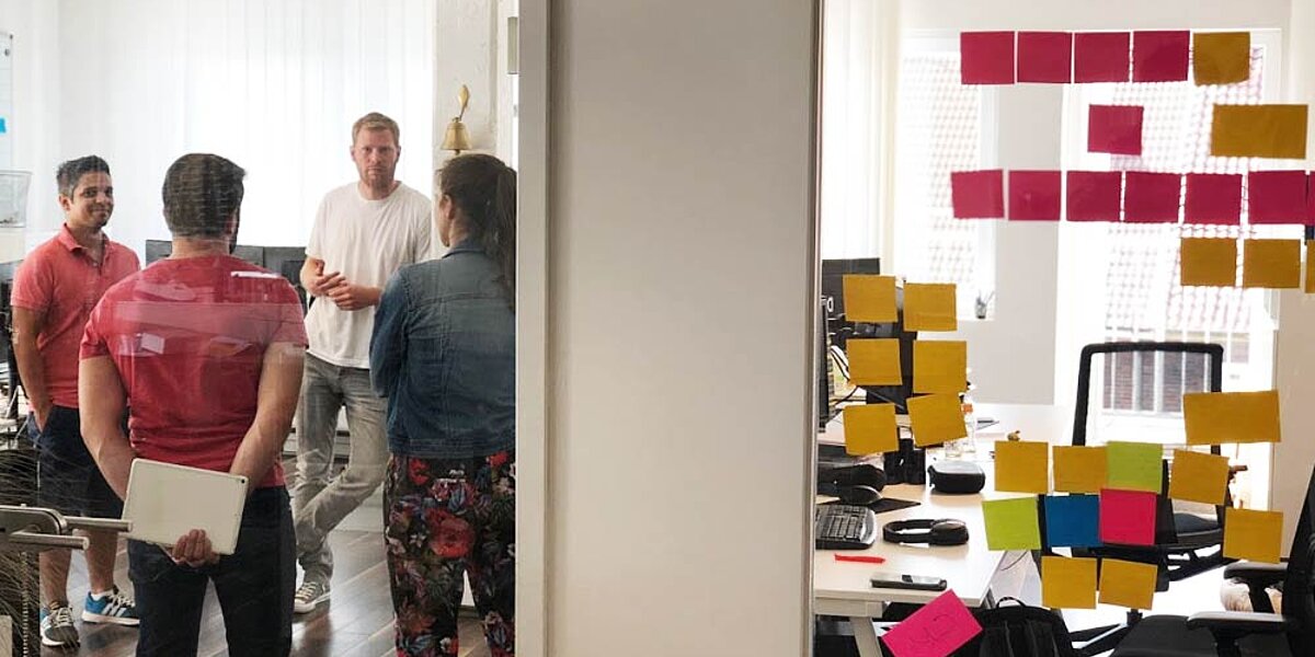 Mitarbeitende der B2B Digitalagentur digit.ly bei der Projektplanung in einem Glasbüro.