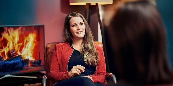 Sarah, HR Managerin bei digit.ly, einer Agentur für Digitales, im Gespräch mit einer weiteren Person vor einem Kamin.