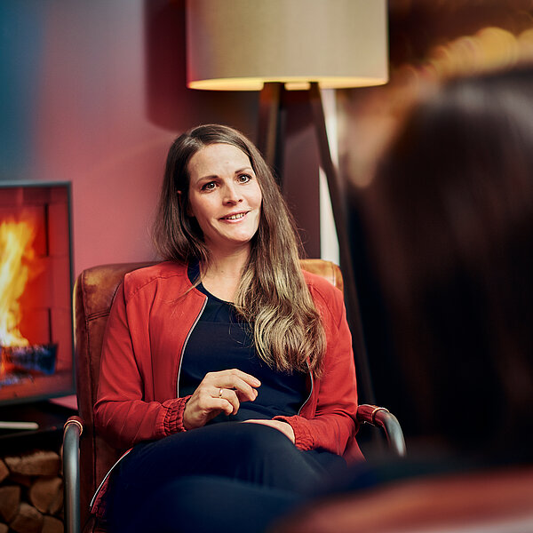 Sarah, HR Managerin bei digit.ly, einer Agentur für Digitales, im Gespräch mit einer weiteren Person vor einem Kamin.