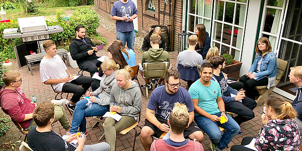 Das Team einer B2B Digitalagentur sitzt im Garten beim MItarbeitendengrillen.