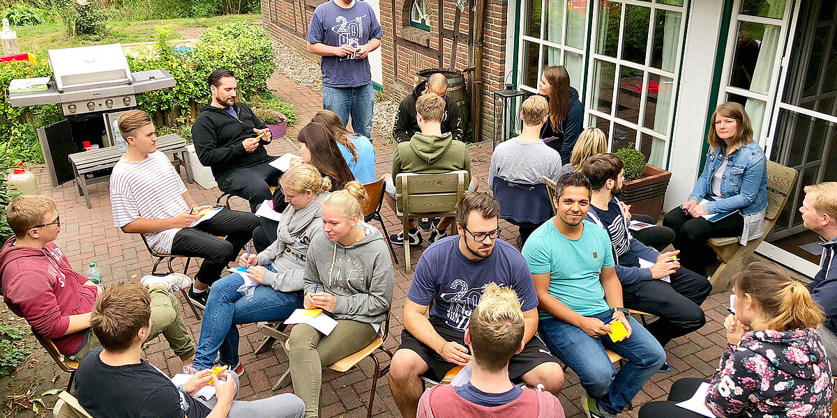 Das Team einer B2B Digitalagentur sitzt im Garten beim MItarbeitendengrillen.