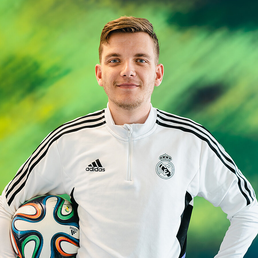 Phil, Webentwickler bei der B2B Digitalagentur digit.ly in Hannover, posiert im Trikot mit einem Fußball unterm Arm.