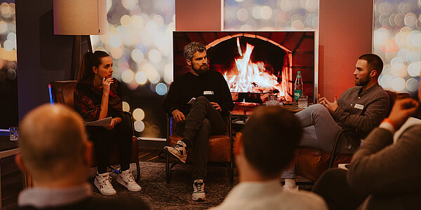 Mitarbeitende von digit.ly, Digitalagentur aus Hannover, und Gäste einer Vortragsreihe sitzen zusammen in einem gemütlichen Raum mit Kamin.