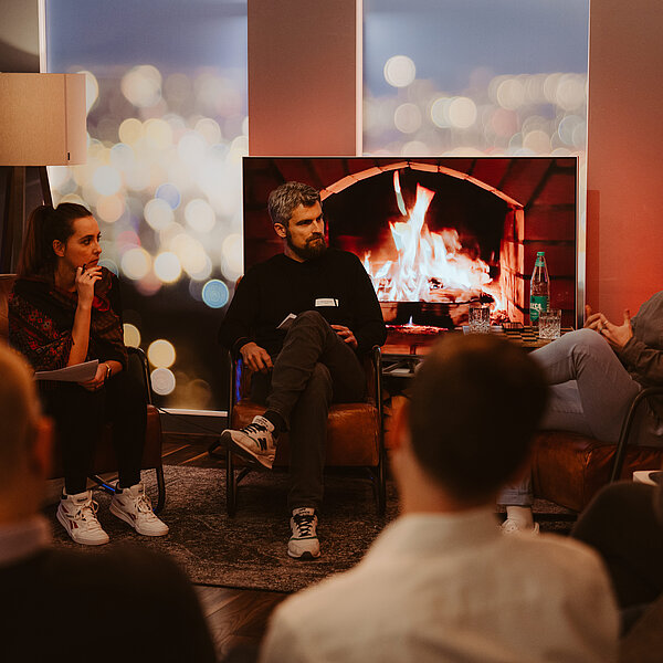 Mitarbeitende von digit.ly, Digitalagentur aus Hannover, und Gäste einer Vortragsreihe sitzen zusammen in einem gemütlichen Raum mit Kamin.