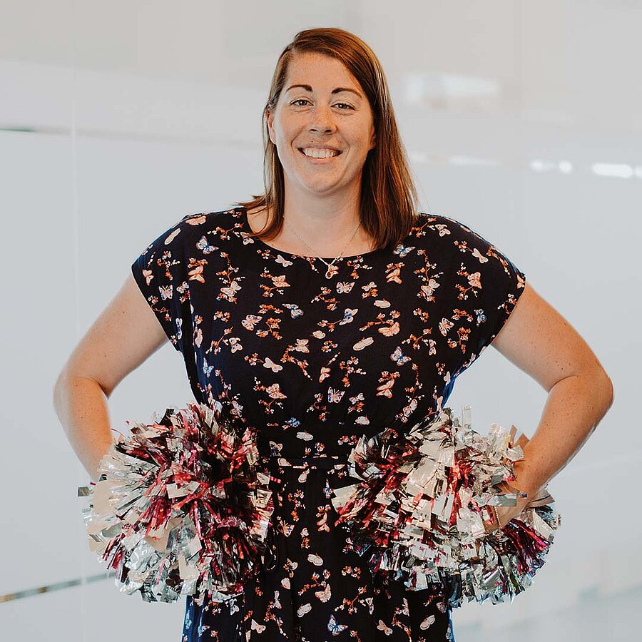 Theresa, Office Managerin bei der B2B Digitalagentur digit.ly in Hannover, posiert mit Pompons.