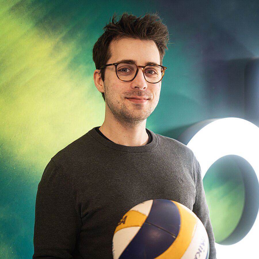 Anton, Frontendentwickler bei der B2B Digitalagentur digit.ly in Hannover, hält einen Volleyball in den Händen.