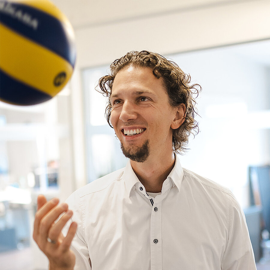 Bastian, Geschäftsführer bei der B2B Digitalagentur digit.ly in Hannover, schaut auf einen Volleyball, den er hochwirft.